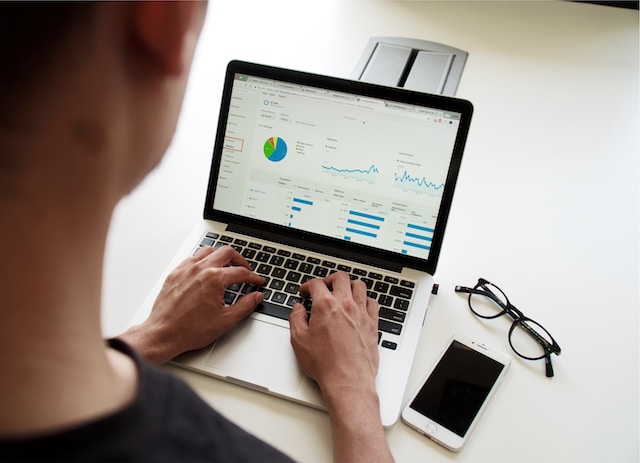 صورة لرجل يحلل سلوك المستهلك وإحصائياته على جهاز Macbook.
