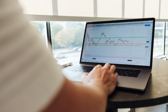 صورة لشخص يشاهد مخطط حركة السعر على جهاز كمبيوتر محمول.