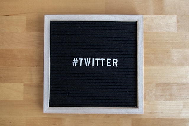 صورة لخلفية سوداء بإطار رمادي على أرضية خشبية عليها نقش "#TWITTER".