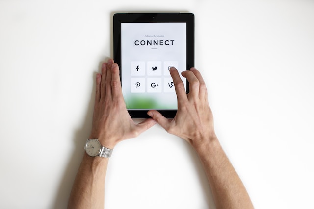 Eine Person interagiert mit einem Tablet mit den Symbolen von Facebook, Twitter, Pinterest, Google+ und anderen Social-Media-Anwendungen.