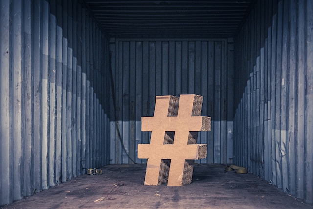 Ein Bild einer braunen Pappillustration des Hashtag-Symbols im Inneren eines Schiffscontainers.