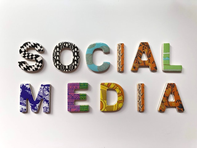Ein Foto des Wortes "SOCIAL MEDIA", das auf einer weißen Wand mit bunt gestalteten 3D-Buchstaben abgebildet ist.