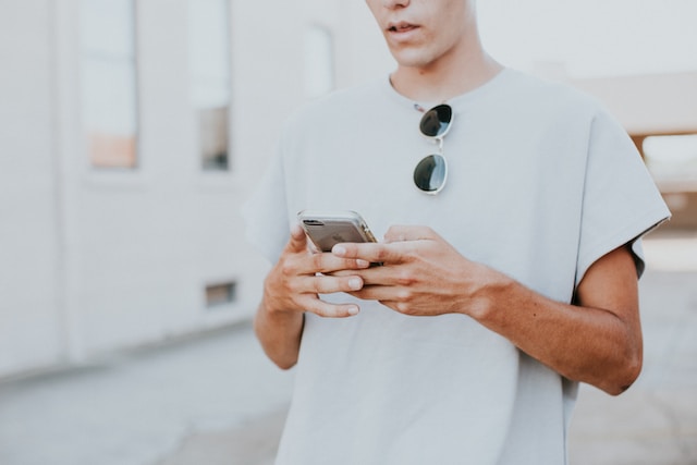  Ein Social-Media-Vermarkter verwendet sein Mobilgerät, um nach Fragen zu suchen, die er stellen kann, um das Engagement für seinen nächsten Beitrag auf X zu erhöhen.