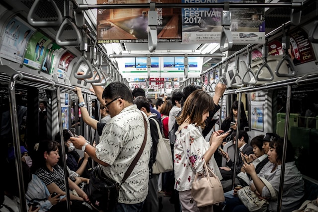 Menschen in einer überfüllten U-Bahn schauen auf ihre Telefone.