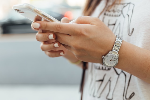 Eine Person trägt eine graue Uhr und hält ein Telefon mit einem durchsichtigen Gehäuse.
