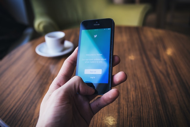 Una imagen de una mano sujetando un iPhone negro que muestra la página de inicio de sesión de Twitter.