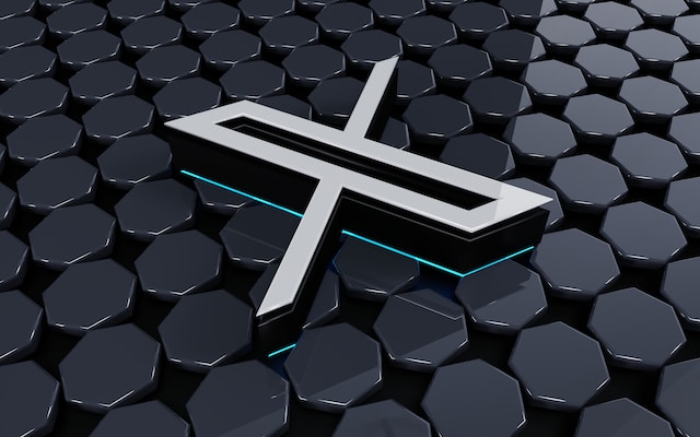 Ilustración en 3D de un logotipo X blanco rodeado de azulejos hexagonales negros.