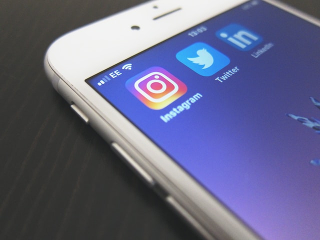 Photo d'un iPhone blanc affichant les applications Instagram, Twitter et LinkedIn.