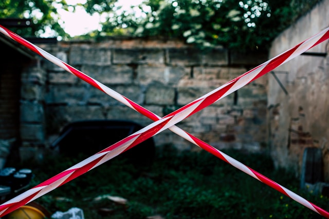 Ruban rouge et blanc en forme de croix devant une zone d'accès restreint.