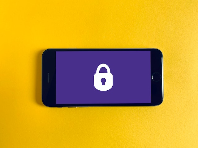 Sebuah iPhone dengan ikon kunci putih dengan latar belakang ungu. 