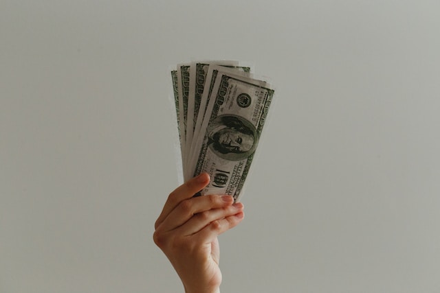 Gambar uang kertas dolar di tangan seseorang.