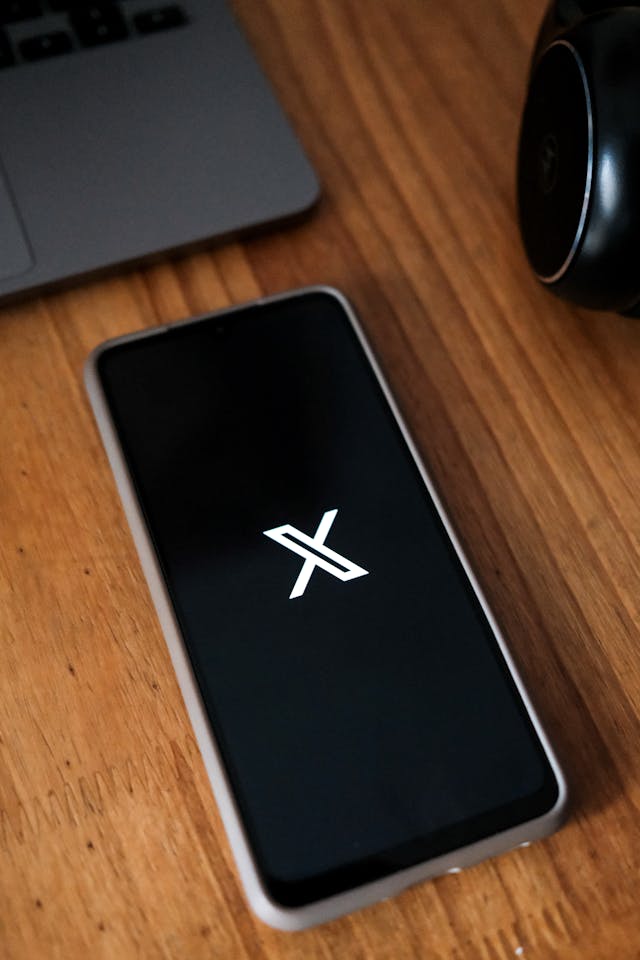 Ponsel cerdas yang menampilkan logo X pada latar belakang hitam.
