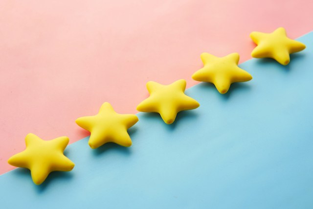 Lima bintang kuning pada batas diagonal latar belakang merah muda dan biru muda.