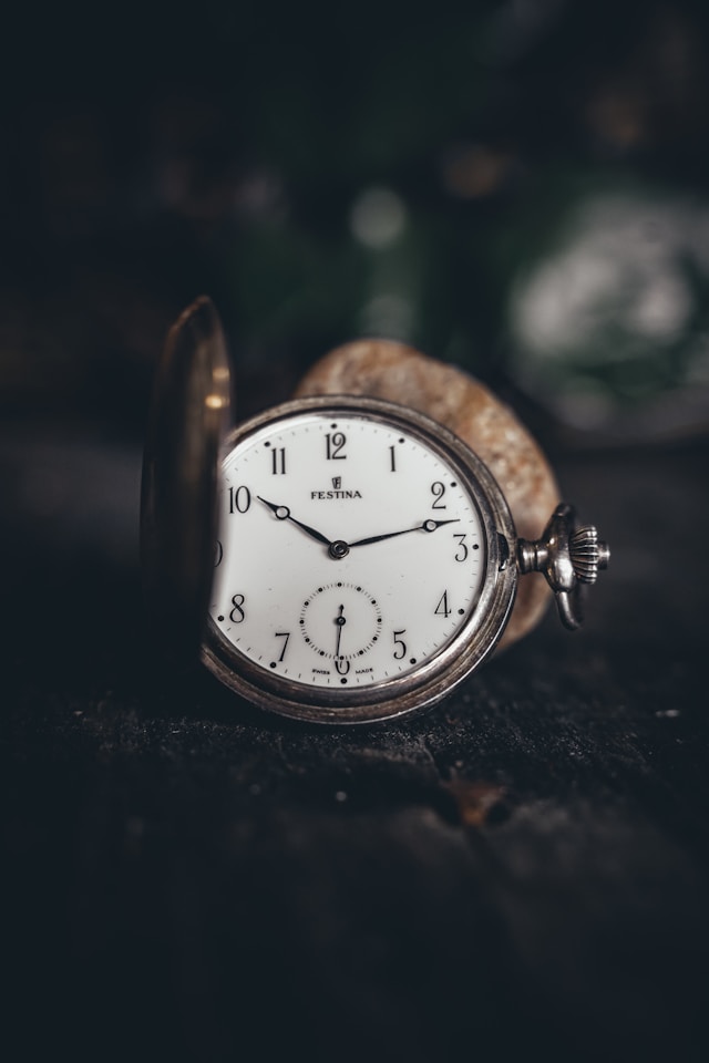 Bidikan close-up arloji saku antik yang menunjukkan waktu.
