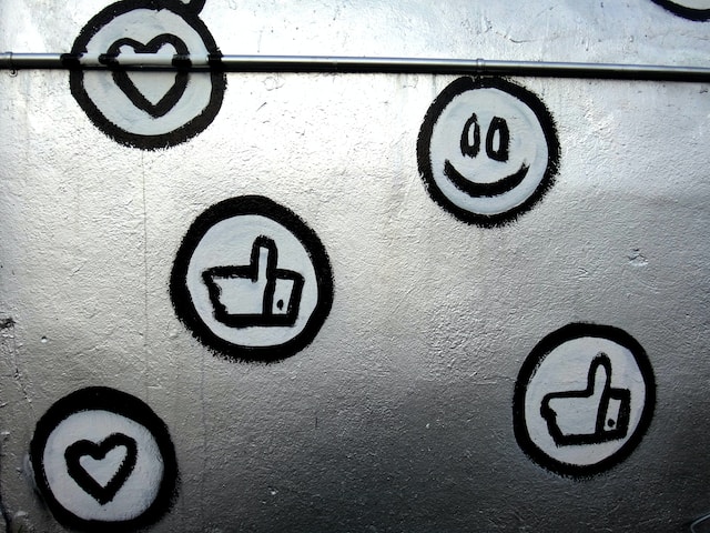 Una foto di un muro su cui sono state dipinte emoji dei social media e varie icone Like.