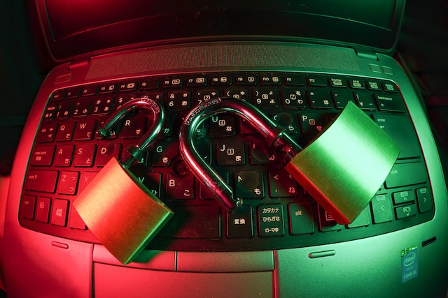 キーボードの上に鍵のかかっていない南京錠が2つあり、赤と緑の照明がついているウィンドウズ・ノートパソコン。