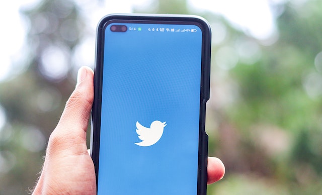 ウェルカムページにツイッターの鳥が表示された携帯電話を持つ人の写真。