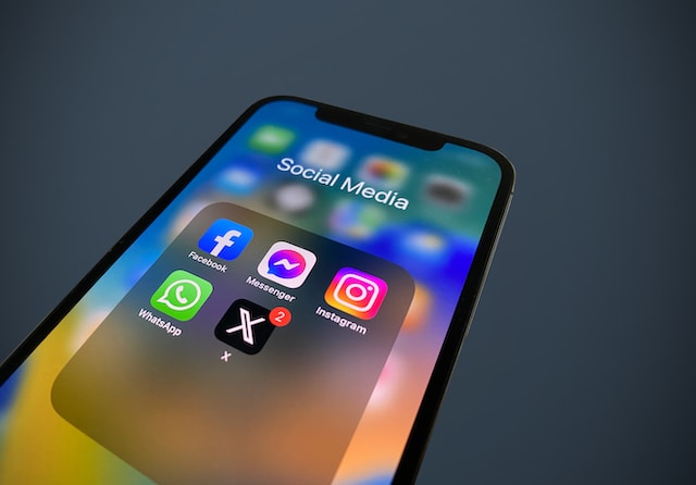 Een close-up foto van een mobiele telefoon waarop een tabblad met sociale apps te zien is met de apps Facebook, Instagram, Whatsapp en X.