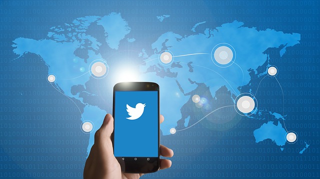 Uma fotografia de um utilizador a abrir o Twitter num smartphone e um mapa-mundo azul com pontos de telecomunicações em várias regiões.
