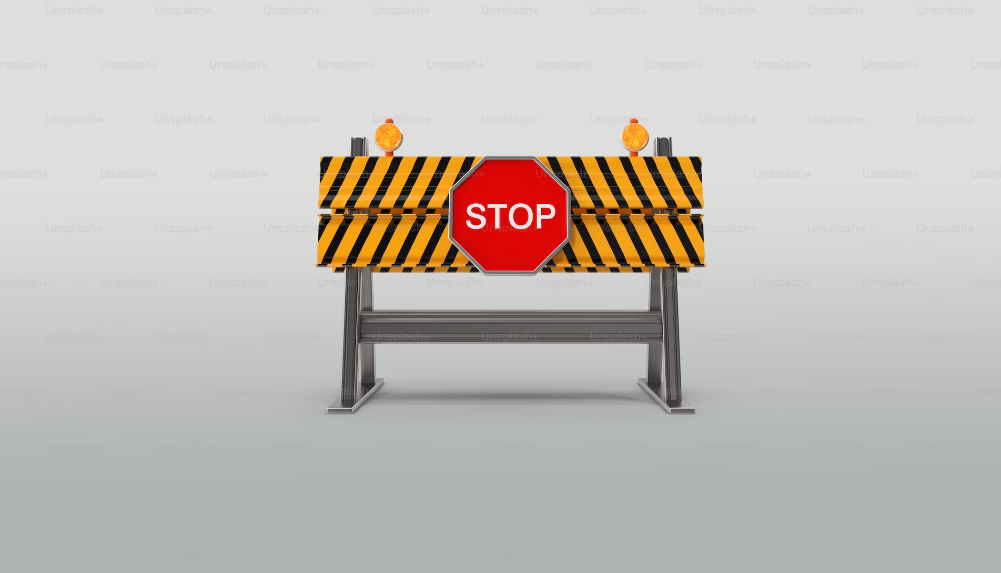 Uma imagem de um sinal de stop vermelho montado num bloqueio de estrada em metal.