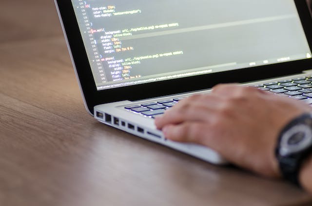 Uma fotografia de alguém a escrever código informático no seu Macbook.