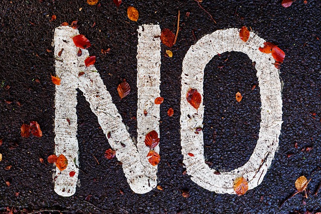 A palavra "Não" em tinta branca numa estrada com folhas espalhadas à volta.
