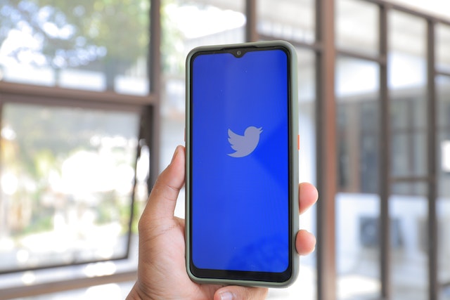 A photograph of a smartphone displaying Twitter’s blue welcome screen