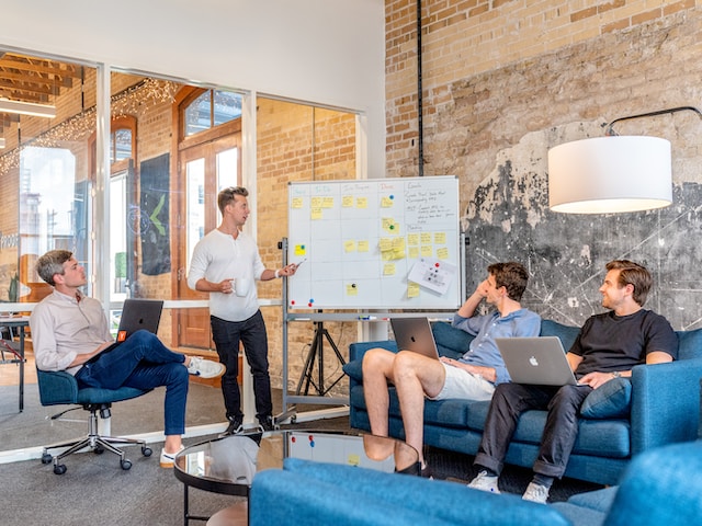 Four people in a meeting, brainstorming ideas and making notes on a whiteboard.