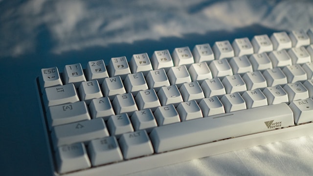 A white mechanical keyboard showing all the alphabets, numbers, and special characters.