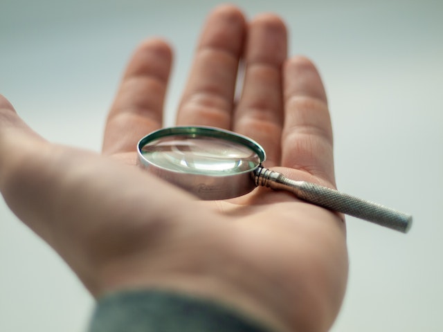 A magnifying glass placed on a person’s palm.