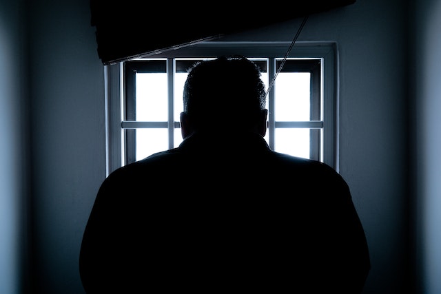 A person looking at a window with bars. 
