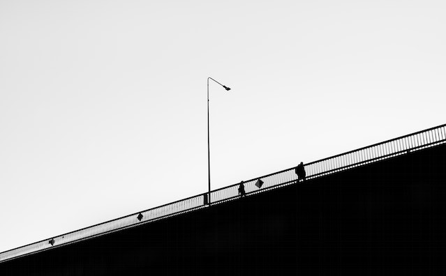 A vintage black and white photo of two people walking on a bridge.