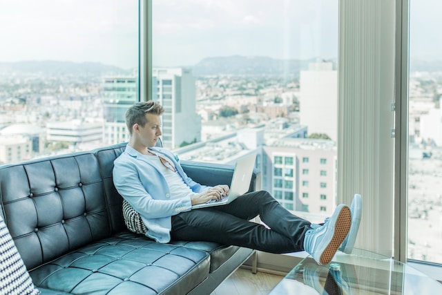 A picture of a person using a laptop sitting on a sofa.