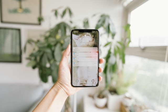 A person holding an iPhone with several Twitter notifications on the lock screen.