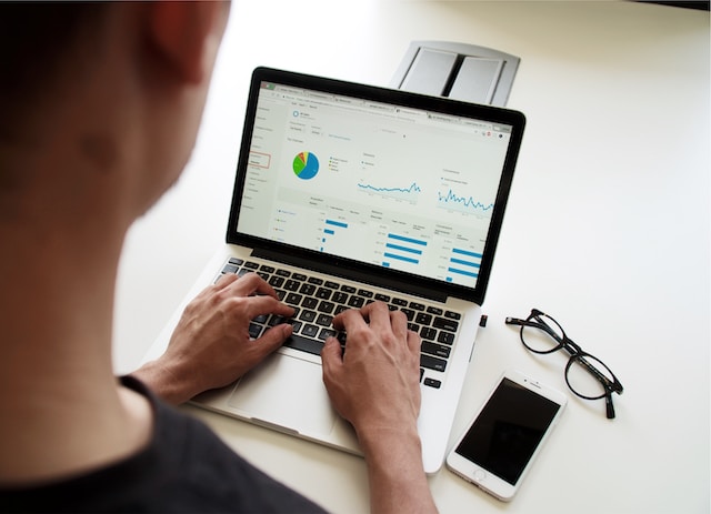 A picture of a man analyzing consumer behavior and statistics on a Macbook.