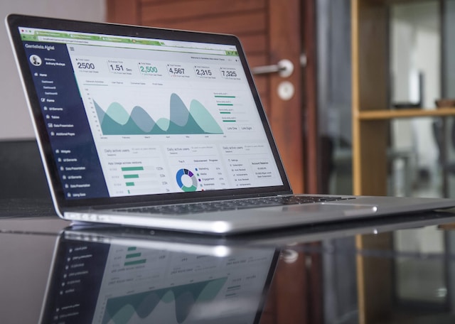 A picture of a laptop on a glass table displaying user statistics.