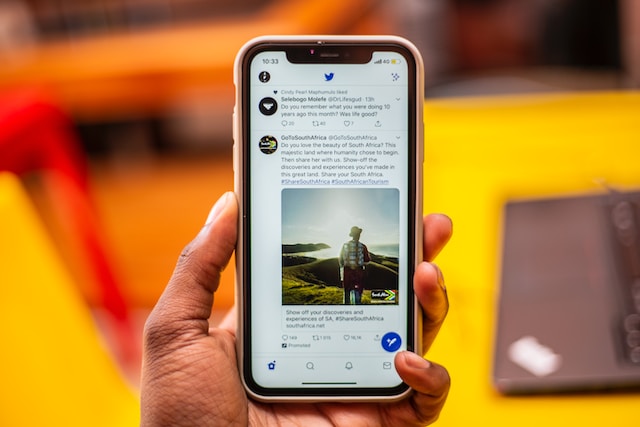 A picture of a hand holding a silver iPhone displaying a Twitter feed