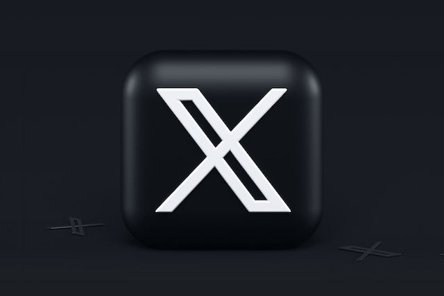 A 3D image of a Black cube with Twitter’s X symbol painted on the face, depicted on a dark background.