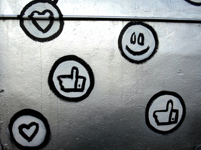 A photo of a wall with social media emojis and various Like icons painted on it.