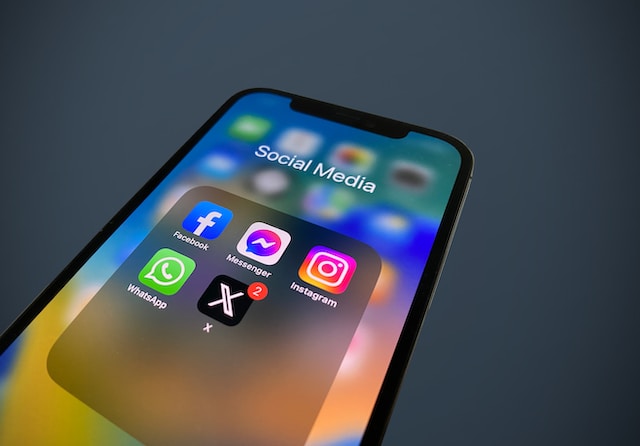 A picture of a close-up view of the X mobile app and other social media mobile apps in a designated folder.