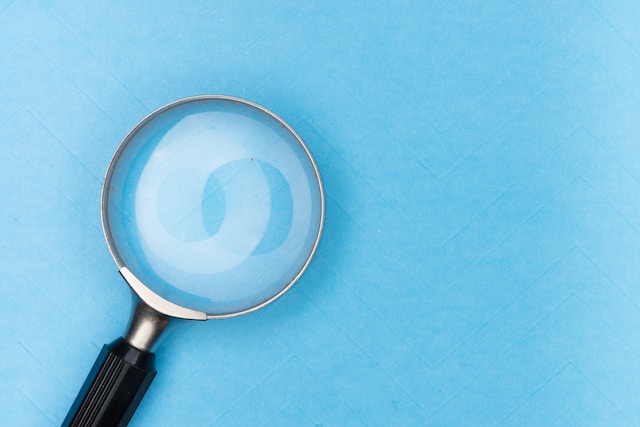 A picture of a magnifying glass which represents Twitter’s search icon on a blue surface.