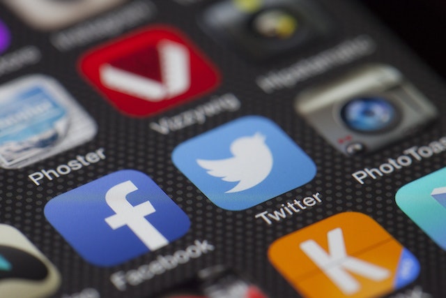 A closeup picture of a phone screen showing multiple apps, including Facebook and Twitter.