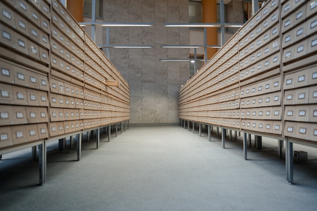 A photograph of a physical archive with tiny labeled shelves in a large hallway.