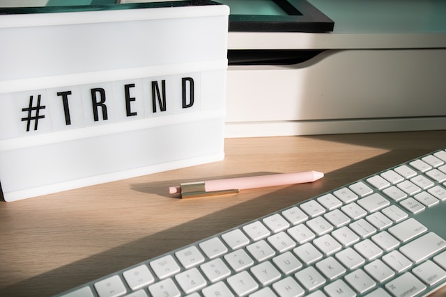 Fotografía de un teclado, un bolígrafo y una caja de luz con la inscripción "#TREND" sobre una mesa.