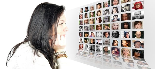A picture of a woman facing a photomontage of many people on a screen.
