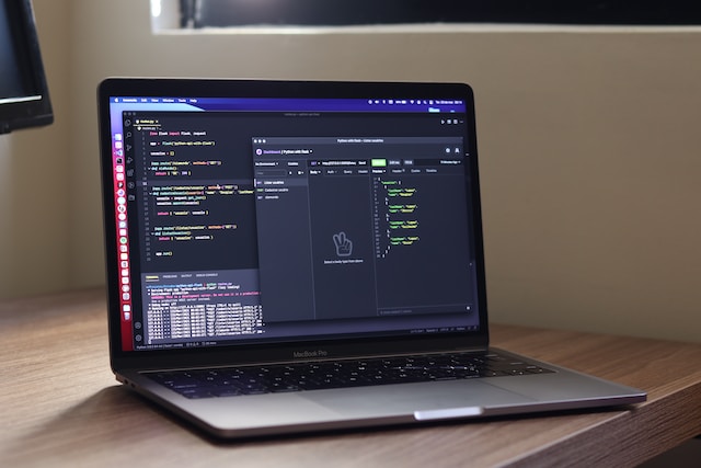 A picture of a laptop on a wooden table with code on its screen.