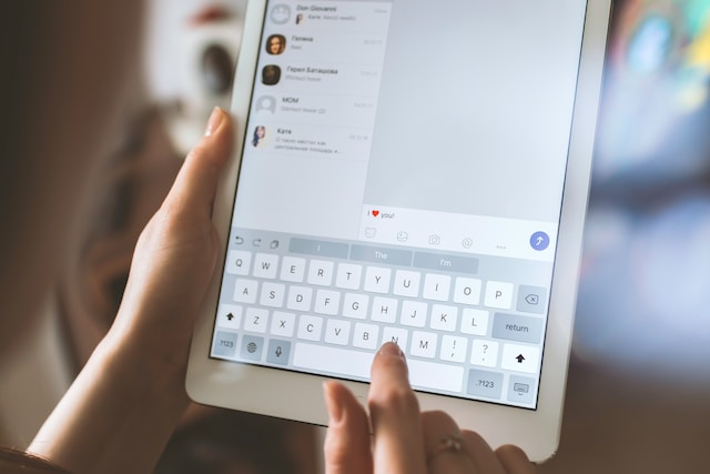 A picture of someone typing a message on a white tablet.