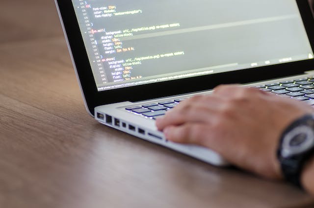 A photo of someone writing computer code on their Macbook.