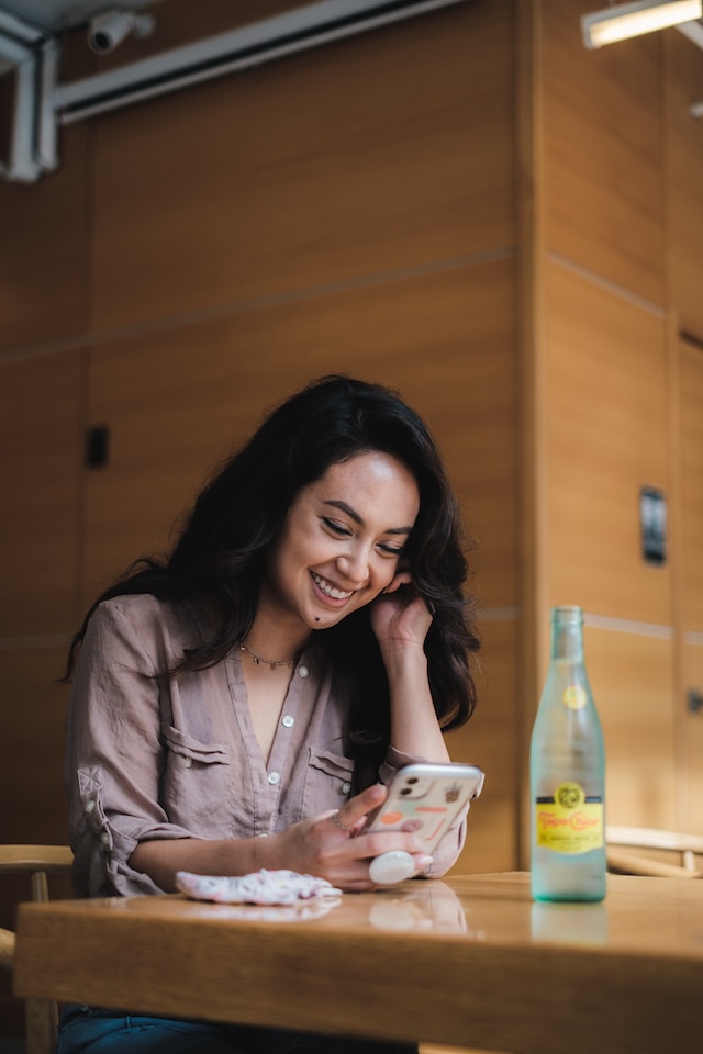 A Twitter user hosts X Space from her iPhone while at a wooden table.