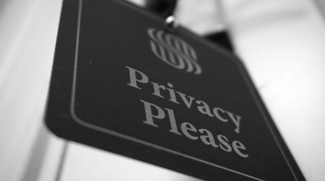 A closeup picture of a black slanted sign with the phrase “Privacy Please” written on it.
